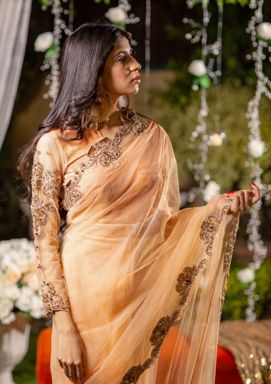 Peachy net saree with copper and peachy embeelished on pallu and border of saree and on blouse as well. Same peachy color blouse on velvet fabric looks elegant for the event.